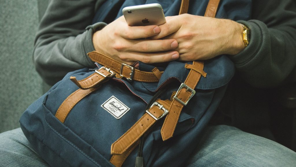 bag and man looking at his emails on his iphone