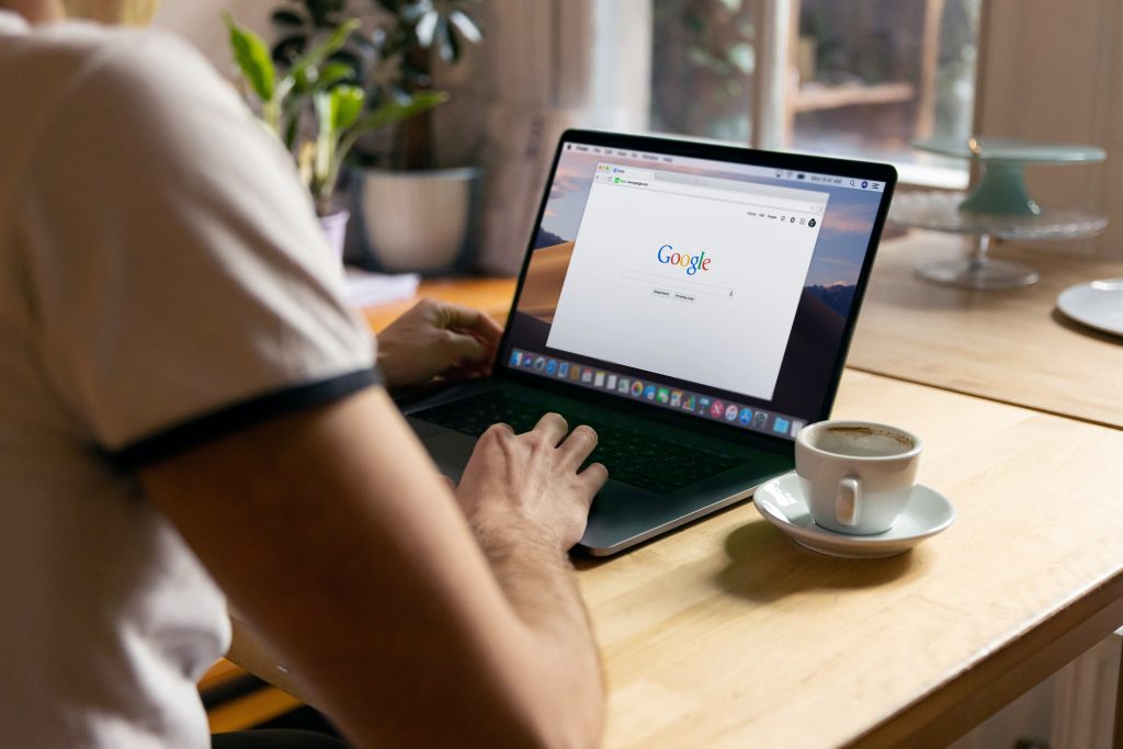 man typing into google on a laptop